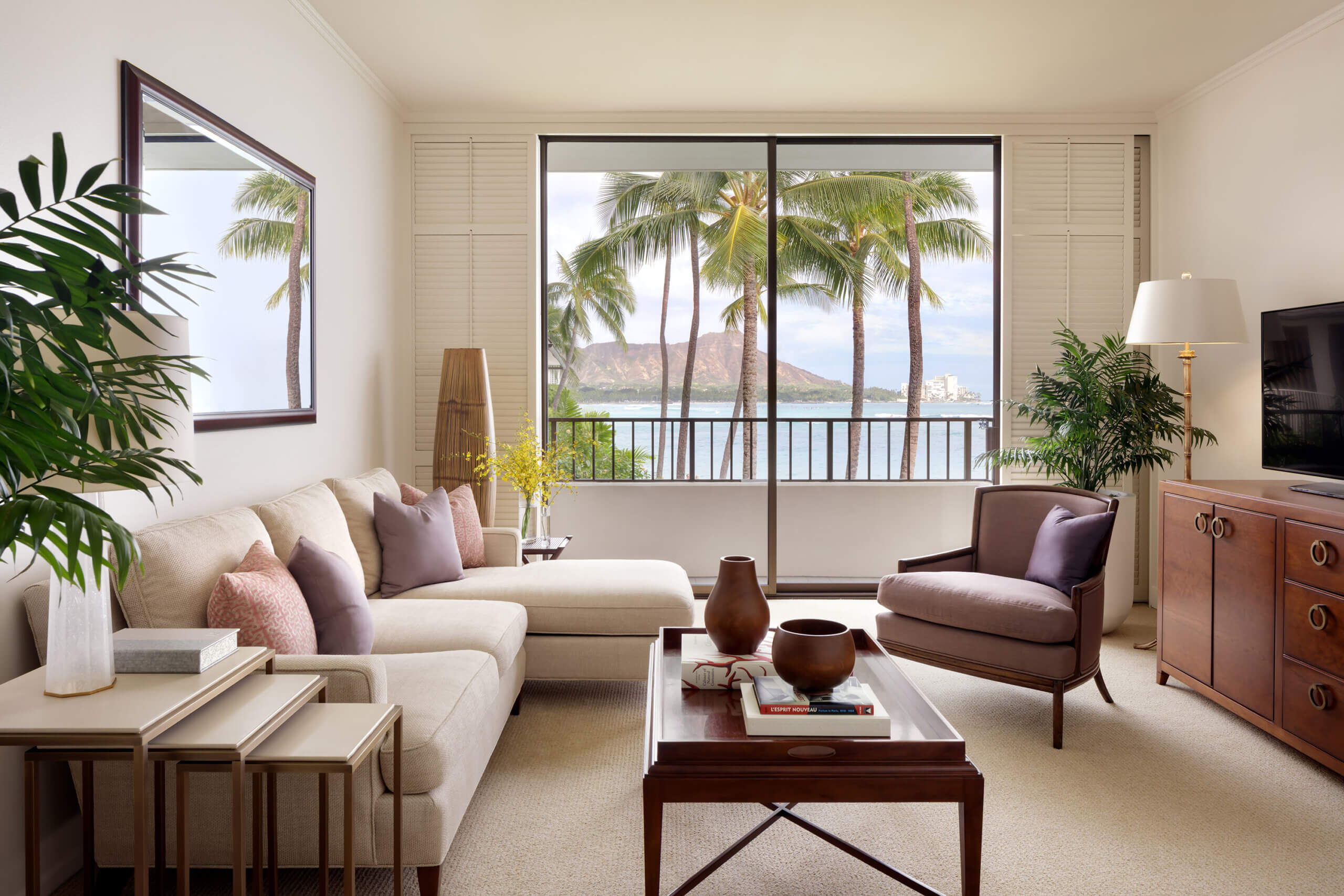 A luxurious living room with a view of palm trees and a body of water.